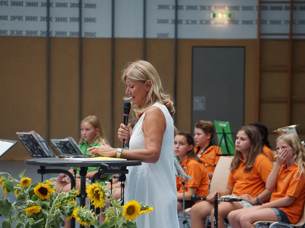 Person spricht ins Mikrofon, daneben Sonnenblumen.
